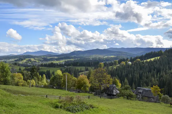 Picturesque landscape with a view of the mountain landscape, green meadows and forest. Rural houses located on the slopes of the mountains. Carpathians, Ukraine