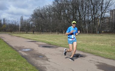 Koşucular, şehir parkındaki bir koşu yarışmasında duygularını gösteren resimler için poz veriyorlar
