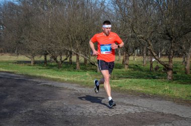 Koşucu yarışmasında koşan genç bir adamın görüntüsü. Koşu kıyafetli erkek sporcu dışarıda koşuyor..
