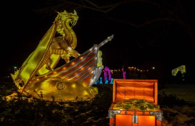 Altın bir ejderha şeklinde hafif bir yapı, hazine sandıklarıyla çevrili bir teknede duruyor. Sokak feneri festivali, Çin Yeni Yılı