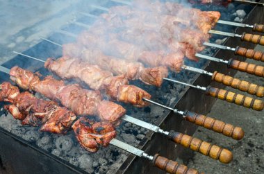 Kömür ızgarasında pişen sulu ızgara et şişleri lezzetli bir koku yayıyor. Barbekü tarifleri, açık hava yemekleri veya mutfak teknikleri ile ilgili makaleler veya bloglar için görsel içerik