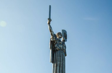 Muhteşem metalik Ana Ukrayna heykeli bir eliyle havada bir kılıç diğer eliyle de açık mavi gökyüzüne karşı mızraklı bir kalkan tutuyor. Kyiv