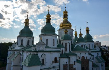 Kyiv 'deki Aziz Sophia Katedrali' nin resmi, her yeşil ve altın kubbenin zirvesini süsleyen haçlarla, yumuşak bulutlarla süslenmiş, dingin bir gökyüzünün arka planına karşı.