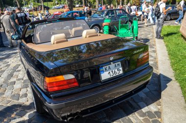 Rear view of black compact executive car 1997 BMW E36 328i sport cabriolet is a very smart modern classic produced by the German automaker BMW clipart
