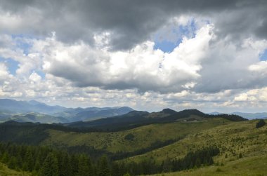 Yuvarlanan tepelerin ve bulutlu bir gökyüzünün altında kaybolan yeşil sıradağların nefes kesici manzarası. Karpat Dağları, Ukrayna