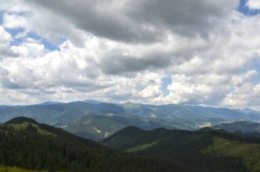 Yuvarlanan tepeleri ve alçak bulutlu gökyüzünün altında uzanan görkemli tepeleri ile nefes kesici dağ manzarası. Karpat Dağları, Ukrayna