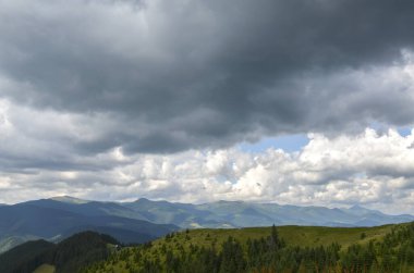Gökyüzünün altında alçak bulutlu dağ sırtı olan yoğun yeşil ormanlarla kaplı engin, yuvarlanan tepelerin olduğu manzaralı bir yer. Karpat Dağları, Ukrayna