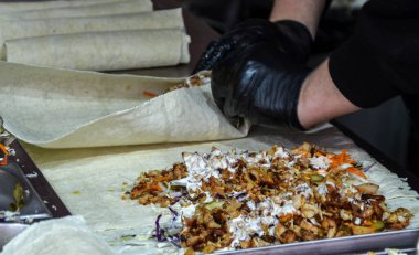 Aşçının elleri siyah eldiven giyer, paket şavurma yapar. Yemek servisi endüstrisi, aşçılık sanatı, fast-rasual yemek işletmeleri, ya da yemek hazırlama