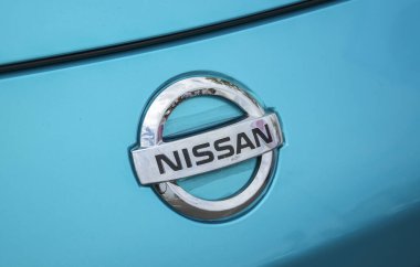 Gümüşe yakın çekim ve parlak mavi bir araba yüzeyindeki Nissan logosu. Otomotiv markaları ve otomobil üretimi