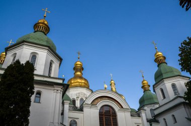 Kyiv 'deki Aziz Sophia Katedrali' nin çarpıcı mimarisi altın haçlarla kaplanmış birden fazla kubbe ile kiliselerin beyaz duvarları, yeşil ve altın kubbeler açık mavi gökyüzüne karşı canlı bir şekilde göze çarpıyor.