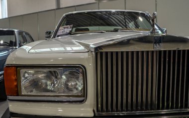 Bir Rolls Royce Silver Spirit 'in ikonik ön farının yakın çekimi zarif krom detaylarını, klasik kıvrımlarını ve lüks tasarımını gözler önüne seriyor.