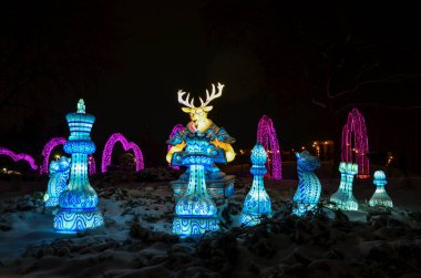 A vibrant display of chess pieces with a reindeer figure, beautifully illuminated against a snowy night backdrop. Captivating holiday light decoration in a winter setting. China Lantern Festival clipart