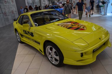 Pürüzsüz, aerodinamik tasarımı ve ayırt edici çizgileriyle 1978 model sarı Porsche 924 klasik Alman spor arabalarının zarafet ve mühendislik hünerlerinin bir örneğidir.