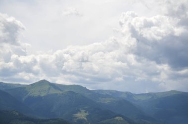 Dramatik bulutlu bir gökyüzü altında dağlık bir arazinin nefes kesici manzarası. Doğal güzellik ve sükuneti sergilemek için mükemmel. Özgeçmiş ve doğa temalı projeler için ideal. Karpatlar, Ukrayna