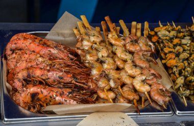 İştah açıcı ızgara karides ve çeşitli deniz ürünleri şişleri bir pazarda sergilenmekte, canlı renkler ve davetkar dokular sergilenmektedir.. 