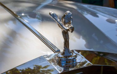 Lüks ve zarafetin sembolü olan Ecstasy 'nin İkonik Ruhu, bir Rolls-Royce aracını süslüyor. Gümüş heykel arabanın arka planında dik duruyor.