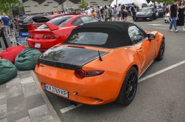 Turuncu spor araba Mazda MX-5 popüler iki koltuklu üstü açık arabasının kendine has geri çekilebilir üstü açık çatısı vardır.