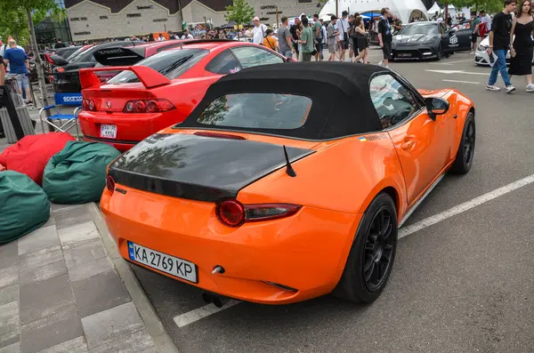 Turuncu spor araba Mazda MX-5 popüler iki koltuklu üstü açık arabasının kendine has geri çekilebilir üstü açık çatısı vardır.