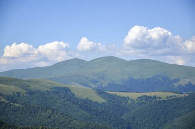 Yeşil tepeleri yuvarlayan ve Blyznytsia Dağı 'nı kabarık bulutları olan açık mavi bir gökyüzünün altında doğanın sükunetini yakalayan görkemli bir manzara. Karpatlar, Ukrayna