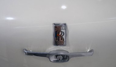 Lüks otomobil markası Rolls-Royce 'un amblemiyle süslenmiş beyaz bir arabanın bagaj sapı birinci sınıf işçiliği ve zarafeti vurguluyor. 