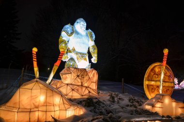 Brightly illuminated sculpture of a mythical gorilla warrior figure surrounded by snowy scenery, with vibrant details offering a captivating and magical atmosphere clipart