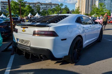 Beyaz Chevrolet Camaro, güçlü motorlu, kendine özgü tasarımı ve heyecan verici sürüş deneyimiyle kalp yakalayan modern bir Amerikan kaslı arabası.