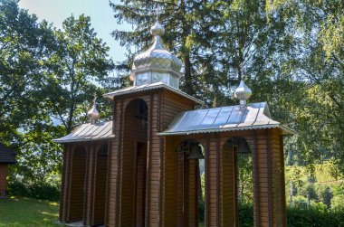 Üç kubbeli ahşap çan kulesi ve Ukrayna 'nın Karpatlar köyündeki Kutsal Bakire Meryem' in Doğumu Kilisesi 'nin metal çatısı.