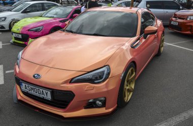 Modifiye edilmiş Subaru BRZ. Eşsiz turuncu boya ve altın tekerlekleri var. Araba, düşük süspansiyon ve ön ayırıcı ile özelleştirildi.