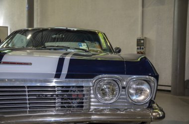 Klasik Chevrolet Impala SS ön detayları ön farlar ve ızgara ile birlikte kaputta koşan belirgin beyaz yarış şeridiyle birlikte gösteriyor. 