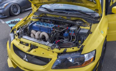 Hood yükseltildi ve Mitsubishi Lancer Evrimi 'nin motor hangarının yenilenmiş borulama manifoldu ve canlı mavi valf kapağı dahil birçok modifikasyonla ortaya çıkarıldı.