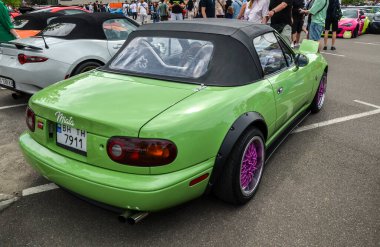 Yeşil Mazda MX-5 Miata, hafif tasarımı ve çevik kullanımıyla tanınan popüler bir roadster sürücü ve makine arasında heyecan verici bir bağlantı sunuyor 