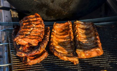 Delicious grilled barbecue pork ribs sizzling on a hot grill, perfect for outdoor gatherings and summer cookouts clipart