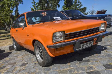 Orange two-door coupe subcompact araba Isuzu Gemini 1st gen (PF50), 1978 Opel Kadett 'in retro araba sergisinde sergilenen bir analogu.