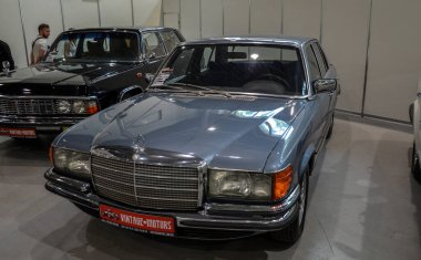 Lüks klasik sedan Mercedes-Benz W116 450SE güçlü V8 motoru, görkemli iç mekanı ve klasik araba fuarında park ettiği zamanına göre gelişmiş teknolojisiyle tanınıyor.