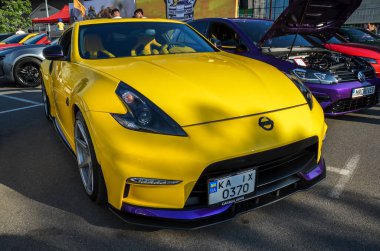 Canlı sarı Nissan 370Z spor arabası, özel tampon ve spoiler ile modifiye edilmiş, agresif duruşunu sergiliyor. 