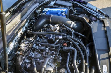 Hortumlar, soğutma sistemleri ve pil de dahil olmak üzere birden fazla bileşeni olan yüksek performanslı bir araba motorunun ayrıntılı görüntüsü