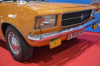 Ön taraftaki parlak turuncu Sedan Opel Rekord 'a yakın çekim ön ızgarası ve farları var. Klasik Avrupa araba tasarımı