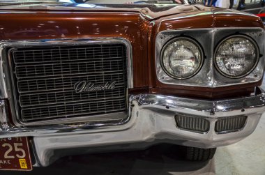 1971 model klasik bir Oldsmobile Delta 88 'in ön ucu belirgin ızgarası, çift yuvarlak farları ve klasik tasarım ekleyen krom tamponu var.