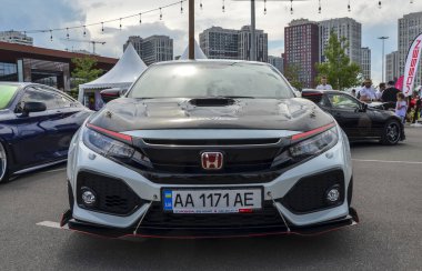Honda Civic R tipi, özel yapım kapüşonlu, kırmızı aksanlı, ve diğer modifikasyonlar sportif ve agresif görünümünü artırıyor, kalabalıktan kendini belli ediyor.