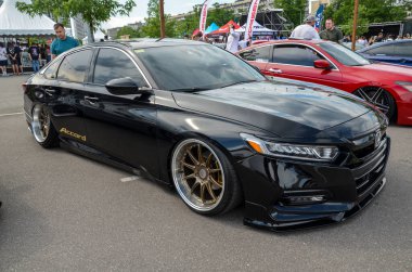 Siyah Honda Accord çarpıcı özel modifikasyonlarla büyük bronz tekerlekler, indirimli süspansiyon ve renkli camlar araba fuarında gururla sergileniyor.