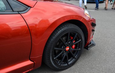 Kırmızı bir spor arabanın ön sol tarafında Mitsubishi Eclipse, kırmızı Brembo fren kalibreleri ile eşleştirilmiş siyah BBS alaşım tekerleklerini vurguluyor.