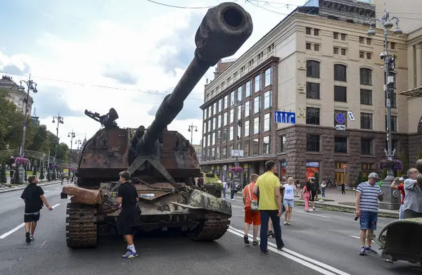 İnsanlar Ukrayna 'nın başkenti Kyiv' de sergilenen bir şehir caddesindeki 2S19 Msta-S numaralı hasarlı Rus askeri güdümlü havan topunun etrafında yürüyorlar.