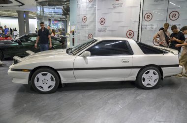 Beyaz spor araba Toyota Supra şık tasarımları, çevik tutumları ve geri çekilebilir farlarının nostaljik cazibesiyle kutlandı.