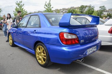 Mavi Subaru Impreza WRX STI 2002, altın tekerlekler ve turbo motoruyla bilinen büyük bir arka spoiler, hepsi teker çekişli ve ralliden esinlenilmiş tasarım