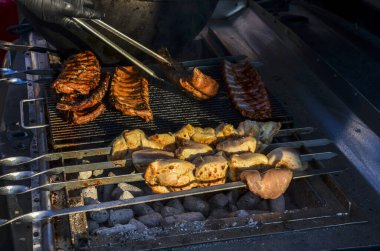 Sıcak bir akşamda kebaplar ve kaburgalar da dahil olmak üzere et seçimleri, leziz bir barbekü hazırlığı sergilenerek ızgara ediliyor.