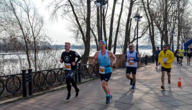 Katılımcılar bir grup maratonu sırasında nehir kenarındaki pitoresk bir patikada koşuyorlar 