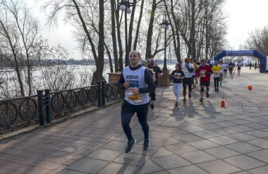 Katılımcılar bir grup maratonu sırasında nehir kenarındaki pitoresk bir patikada koşuyorlar 