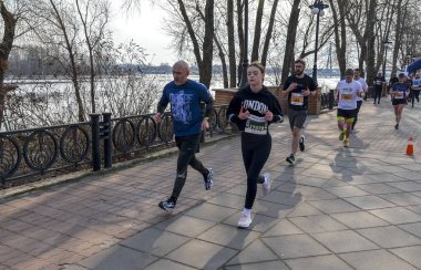 Katılımcılar bir grup maratonu sırasında nehir kenarındaki pitoresk bir patikada koşuyorlar 