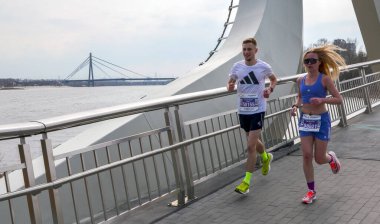 Bir grup hevesli koşucu bir atletizm yarışmasında çağdaş bir köprü yapısında yarışıyor. Görüntü uygunluğun ve kararlılığın özünü yakalar.