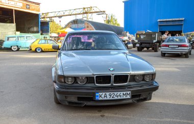 Klasik gümüş sedan 1990 BMW E32 7 Serisi alaşımlı tekerlekler, zamansız tasarım ve lüks bir araç olarak durumunu yansıtan ikonik özellikler